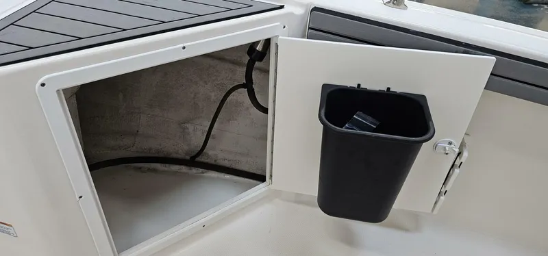 Slide: The Image of Storage compartment on 2018 Yamaha Boats 210 FSH Deluxe with trash bin. - 15