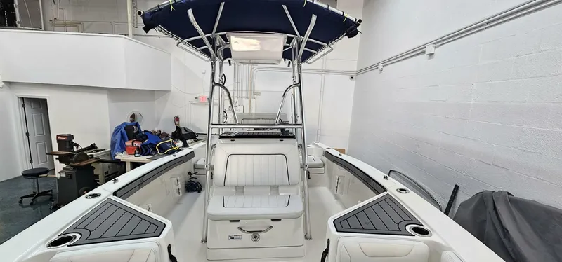 Slide: The Image of 2018 Yamaha Boats 210 FSH Deluxe interior with seating and canopy in a showroom. - 16