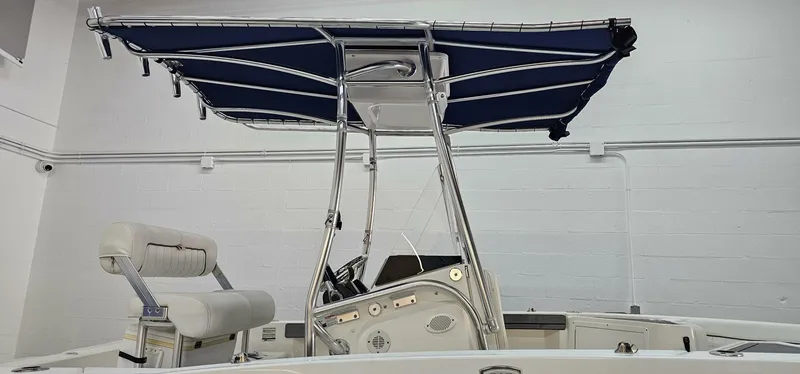 Slide: The Image of 2018 Yamaha Boats 210 FSH Deluxe with blue canopy in indoor setting. - 2