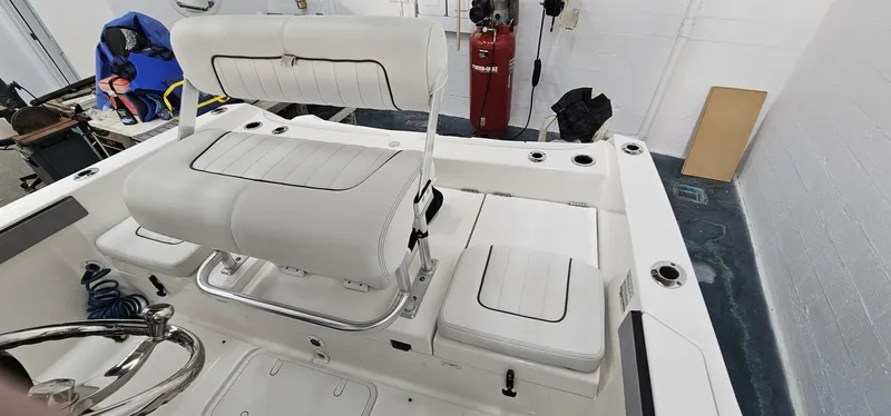Slide: The Image of 2018 Yamaha Boats 210 FSH Deluxe interior with white seating and storage compartments. - 21