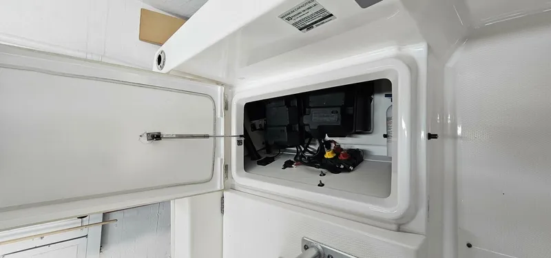 Slide: The Image of 2018 Yamaha Boats 210 FSH Deluxe storage compartment with open hatch and visible wiring. - 22