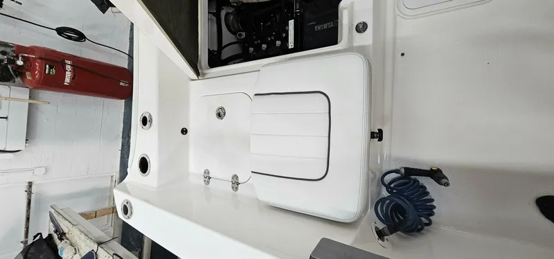 Slide: The Image of 2018 Yamaha Boats 210 FSH Deluxe interior with storage compartments and coiled hose. - 25