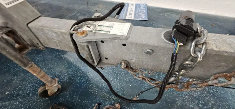 Slide: The Image of Trailer hitch and wiring for 2018 Yamaha Boats 210 FSH Deluxe on a blue speckled floor. - 47