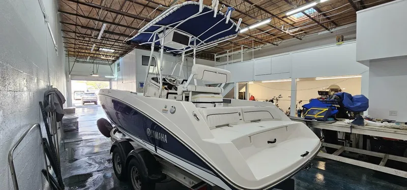 Slide: The Image of 2018 Yamaha Boats 210 FSH Deluxe in indoor storage, rear view. - 5