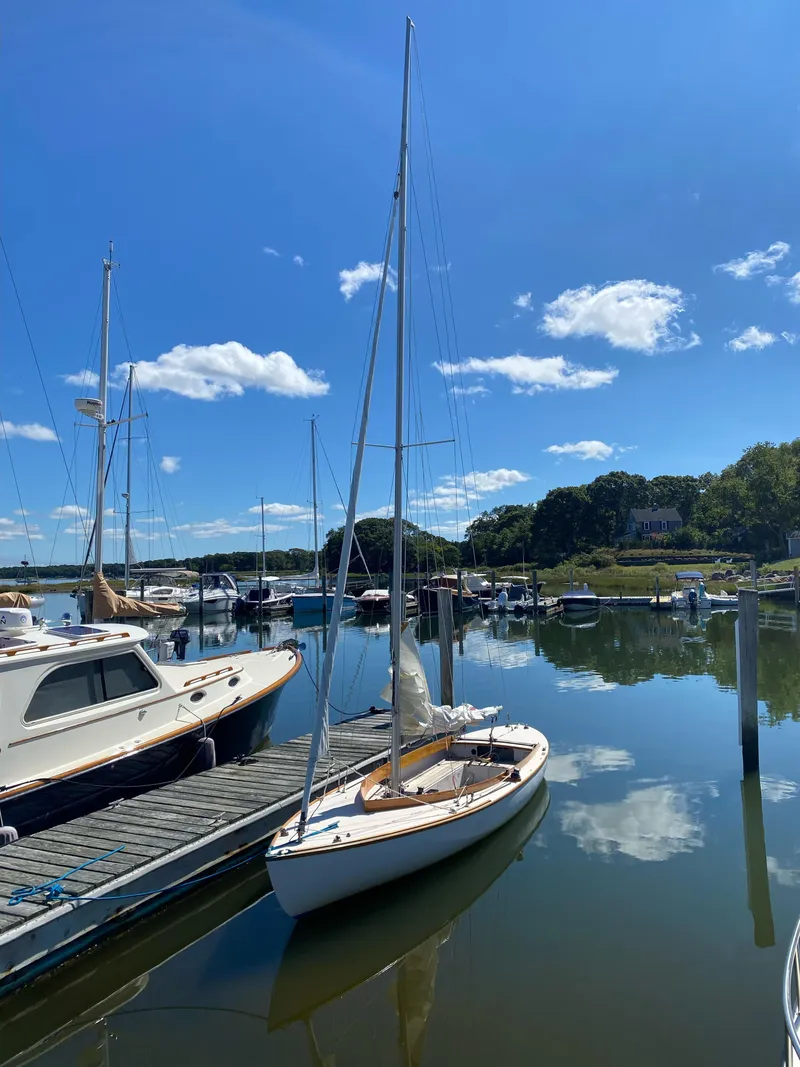 The Image of Sakonnet 23 sailboat docked in a serene marina under a clear blue sky. - 0