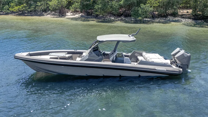 Slide: The Image of 2025 Skipper-BSK 38 boat on calm water near a lush shoreline. - 33