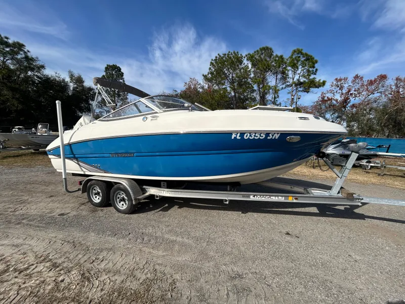 Slide: The Image of 2019 Stingray 240 LR boat on trailer, blue and white, parked outdoors. - 10
