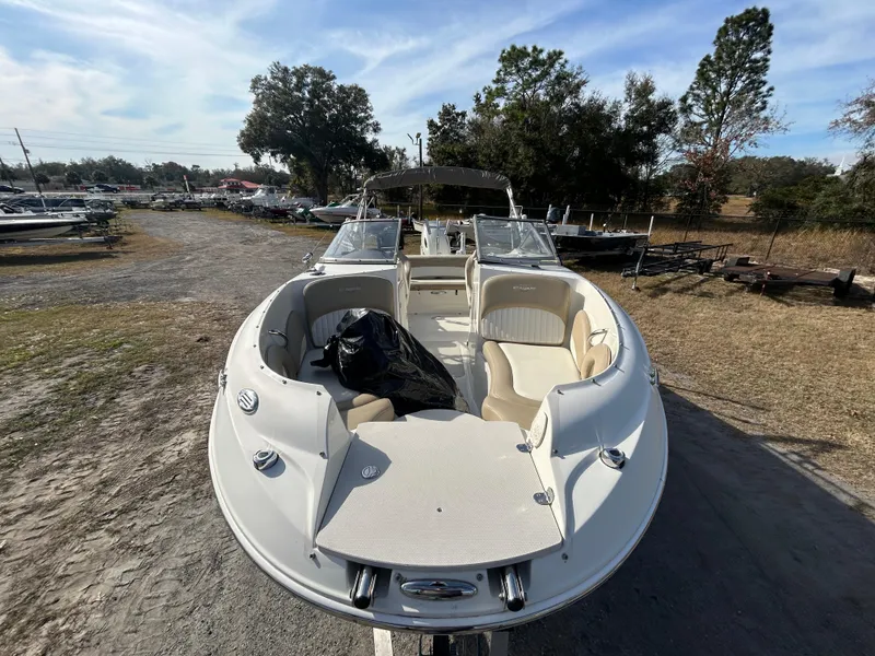 Slide: The Image of 2019 Stingray 240 LR boat with beige seating, parked outdoors on a sunny day. - 11