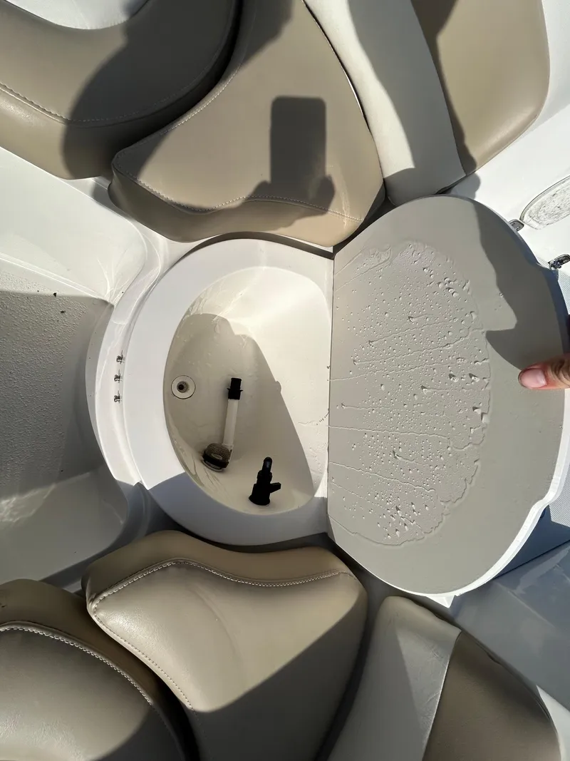 Slide: The Image of 2019 Stingray 240 LR boat interior with open storage compartment and beige seating. - 14