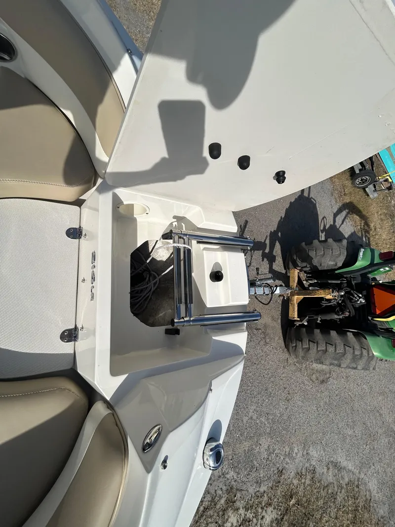 Slide: The Image of 2019 Stingray 240 LR boat with open hatch and ladder, parked near a tractor. - 15