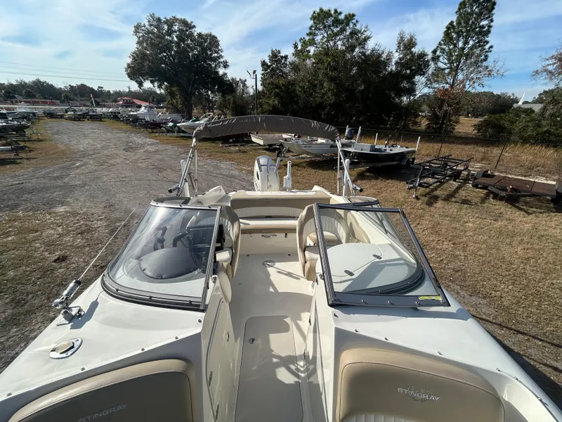Slide: The Image of 2019 Stingray 240 LR boat with open deck and seating, parked outdoors. - 17
