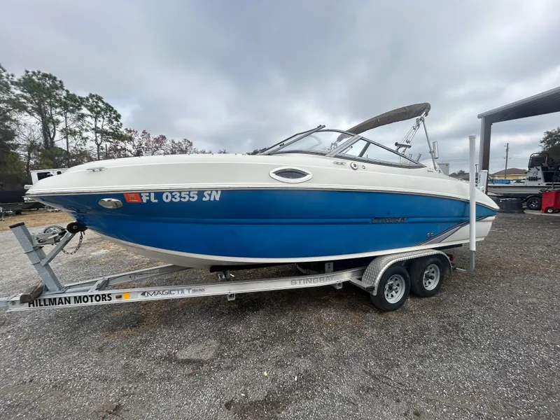 Slide: The Image of 2019 Stingray 240 LR boat on trailer, blue and white, parked outdoors. - 3