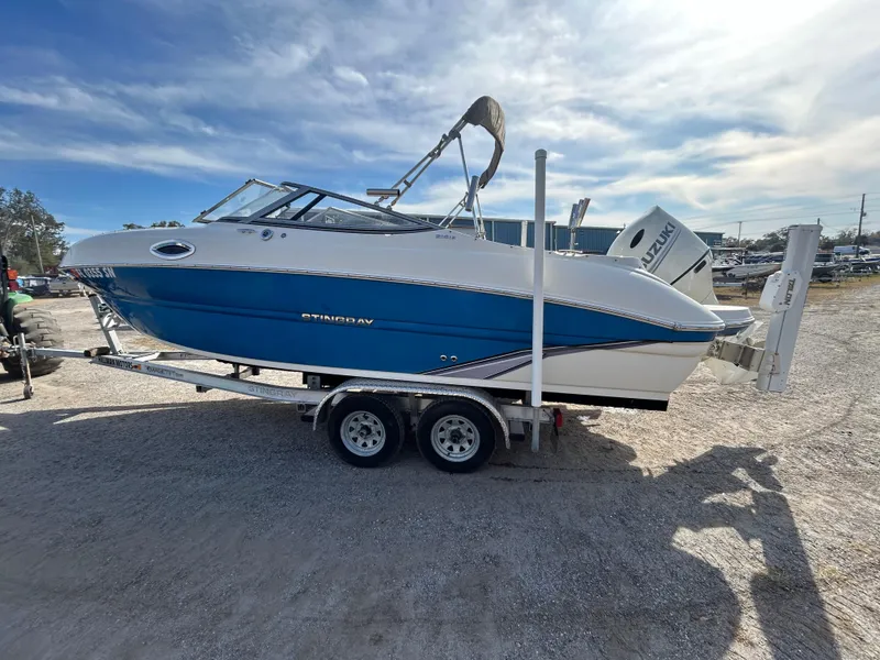 Slide: The Image of 2019 Stingray 240 LR boat on trailer, blue and white design, parked outdoors. - 7