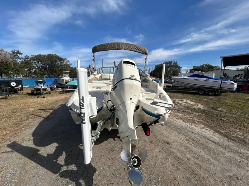 Slide: The Image of 2019 Stingray 240 LR boat with outboard motor, parked outdoors under a clear blue sky. - 8