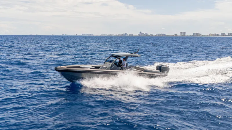 Slide: The Image of 2025 Skipper-BSK 38 boat cruising on open ocean with city skyline in background. - 12