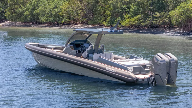 Slide: The Image of 2025 Skipper-BSK 38 boat with dual engines on calm water near lush greenery. - 28