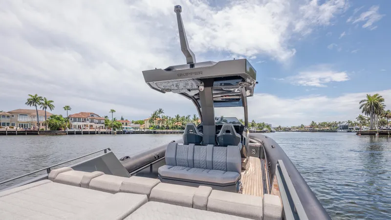 Slide: The Image of 2025 Skipper-BSK 38 boat on a scenic waterway with palm trees and luxury homes. - 40