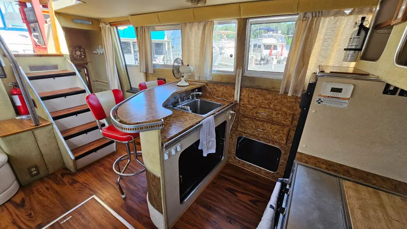 Slide: The Image of Interior of 1983 Chris-Craft 381 Catalina yacht with kitchen, bar stools, and wooden flooring. - 15