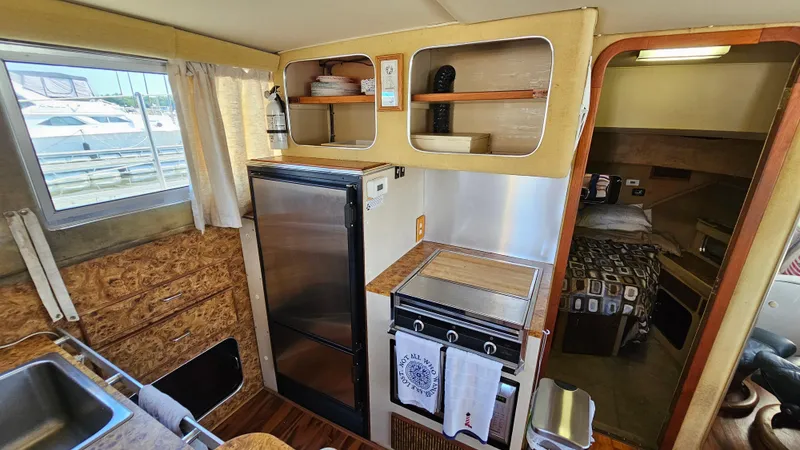 Slide: The Image of 1983 Chris-Craft 381 Catalina interior with kitchen, fridge, and cozy cabin view. - 16
