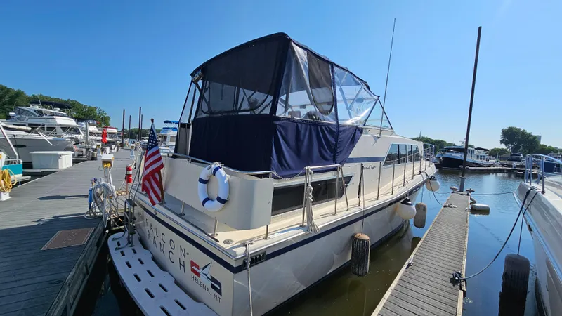 Slide: The Image of 1983 Chris-Craft 381 Catalina yacht docked at marina, featuring American flag and lifebuoy. - 3