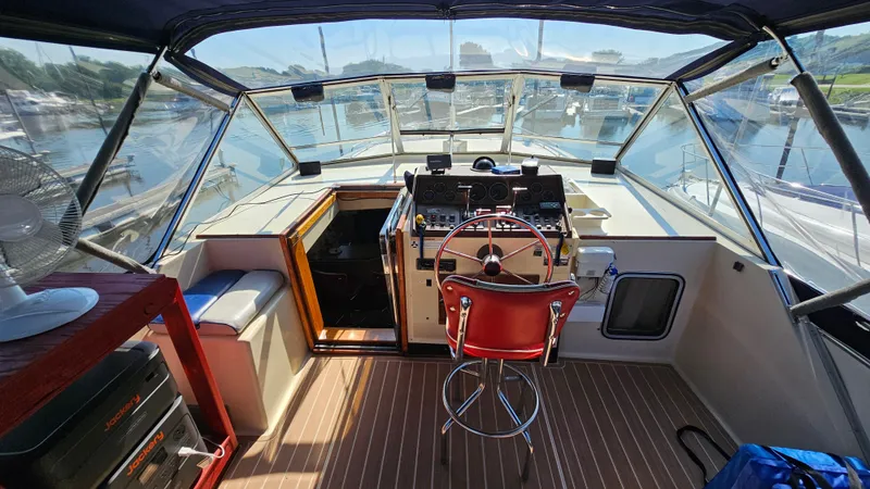 Slide: The Image of 1983 Chris-Craft 381 Catalina helm with red chair, overlooking marina through clear windows. - 8