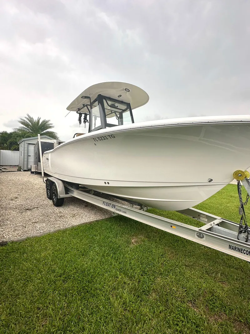 Slide: The Image of 2022 Sea Hunt Ultra 255 SE boat on trailer, parked on grass. - 2