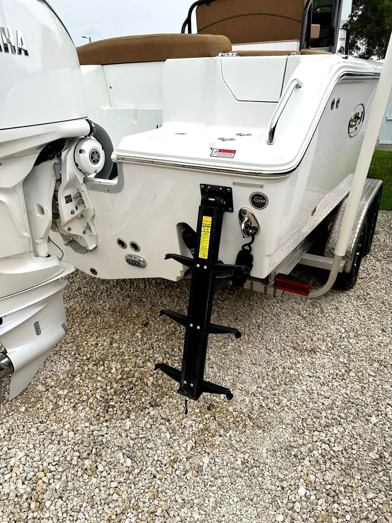 Slide: The Image of 2022 Sea Hunt Ultra 255 SE boat rear view with motor and ladder on gravel. - 7