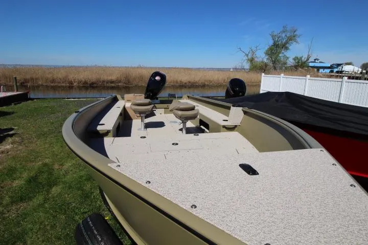 Slide: The Image of 2025 Lund 2075 Alaskan Tiller boat on grassy shore, featuring spacious deck and seating. - 4