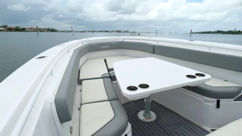 Slide: The Image of 2023 Everglades 365 CC boat interior with seating and table on a calm waterway. - 41