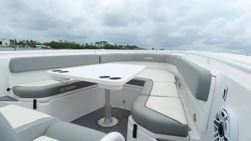 Slide: The Image of 2023 Everglades 365 CC boat interior with cushioned seating and table under cloudy sky. - 42