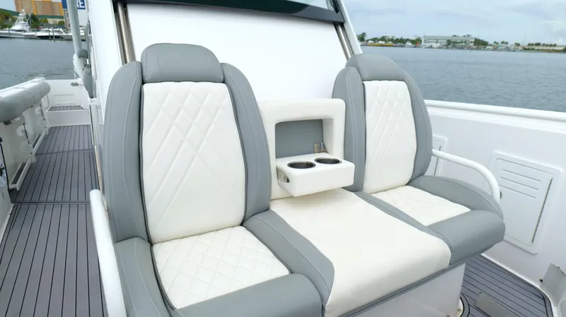 Slide: The Image of Luxury seating on 2023 Everglades 365 CC boat with cup holders, dockside view. - 47