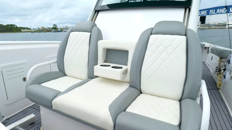 Slide: The Image of Luxury seating on 2023 Everglades 365 CC boat with cup holders, dockside view. - 48