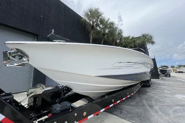 Slide: The Image of 2019 Nor-Tech 450 Sport Center Console boat on trailer, parked near palm trees. - 3