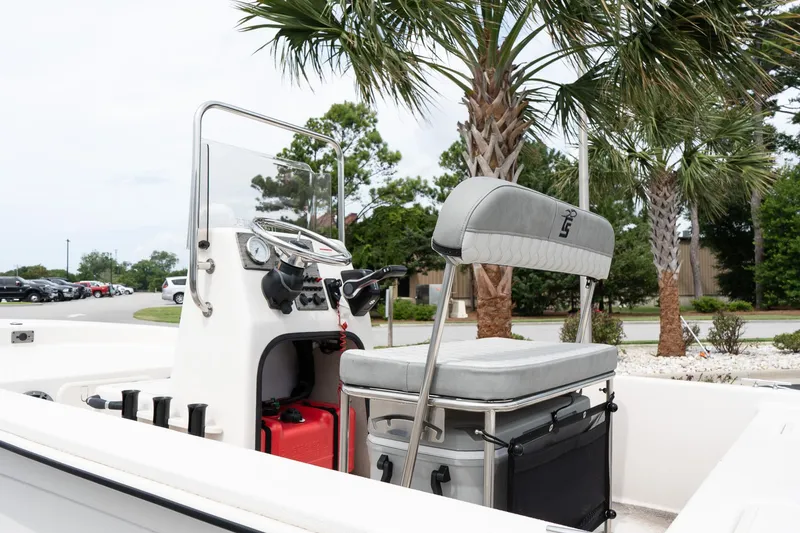 Slide: The Image of 2025 Carolina Skiff E16 JVX CC boat interior with console and seating, surrounded by palm trees. - 6