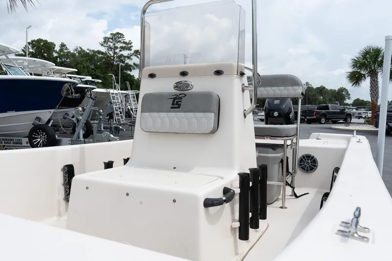 Slide: The Image of 2025 Carolina Skiff E16 JVX CC boat interior with console and seating, parked outdoors. - 8