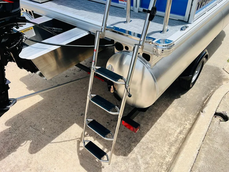 Slide: The Image of 2026 Sun Tracker Party Barge 16 DLX with ladder and motor, parked on concrete. - 11