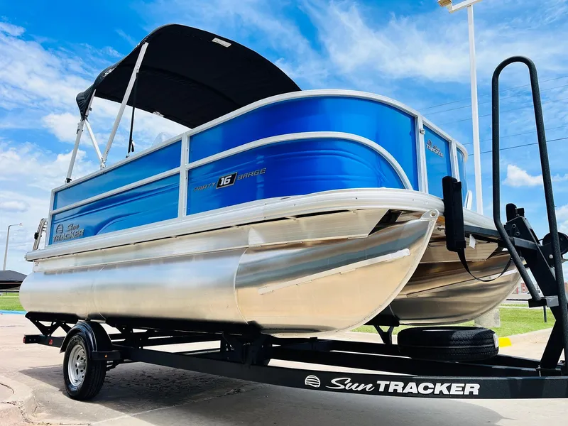 Slide: The Image of 2026 Sun Tracker Party Barge 16 DLX pontoon boat on trailer, blue and silver design. - 4