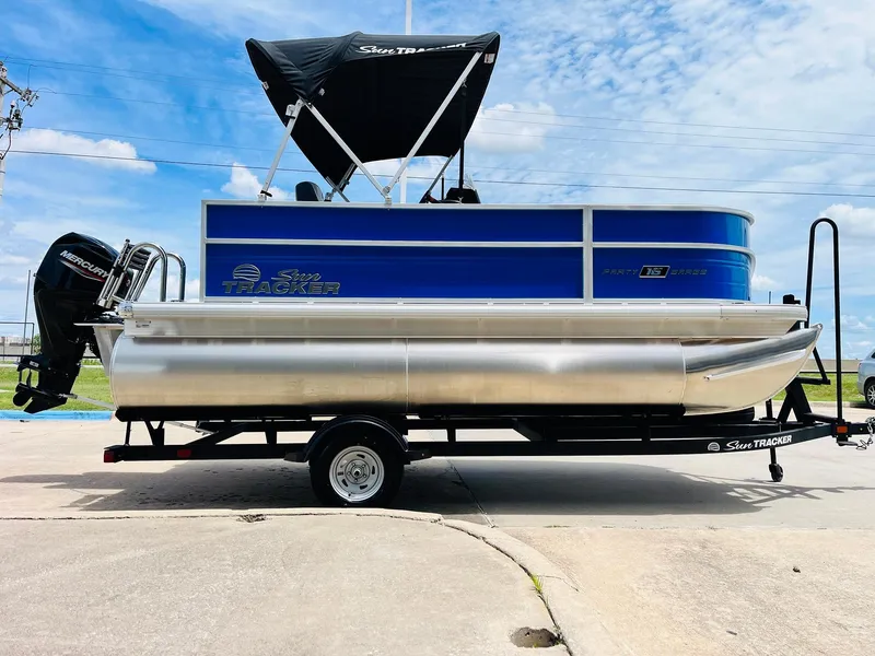 Slide: The Image of 2026 Sun Tracker Party Barge 16 DLX pontoon boat on trailer, blue and silver design. - 5