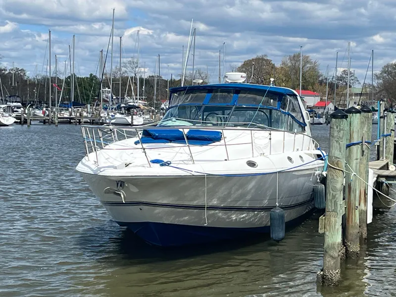The Image of 1998 Cruisers Yachts 4270 Express docked at marina under cloudy sky. - 0