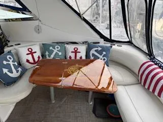 Slide: The Image of 1998 Cruisers Yachts 4270 Express interior with anchor-themed cushions and wooden table. - 1