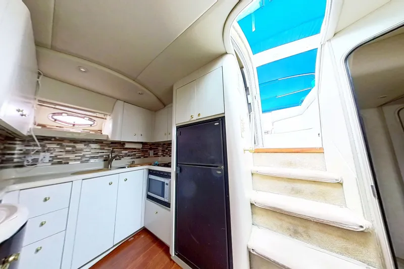 Slide: The Image of 1998 Cruisers Yachts 4270 Express interior kitchen with modern appliances and staircase. - 23