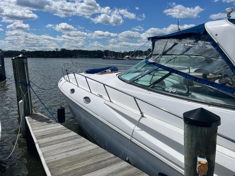 Slide: The Image of 1998 Cruisers Yachts 4270 Express docked by a scenic waterfront under a blue sky. - 26