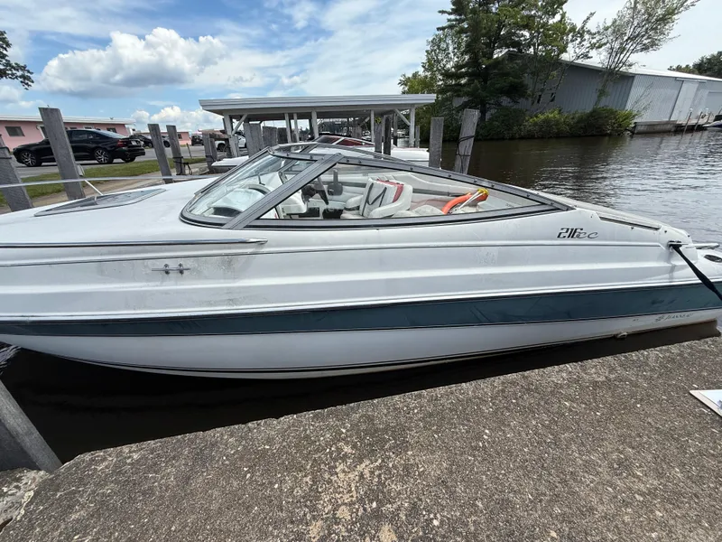 Slide: The Image of 1996 Doral 216 Cuddy boat docked by the water under a partly cloudy sky. - 11