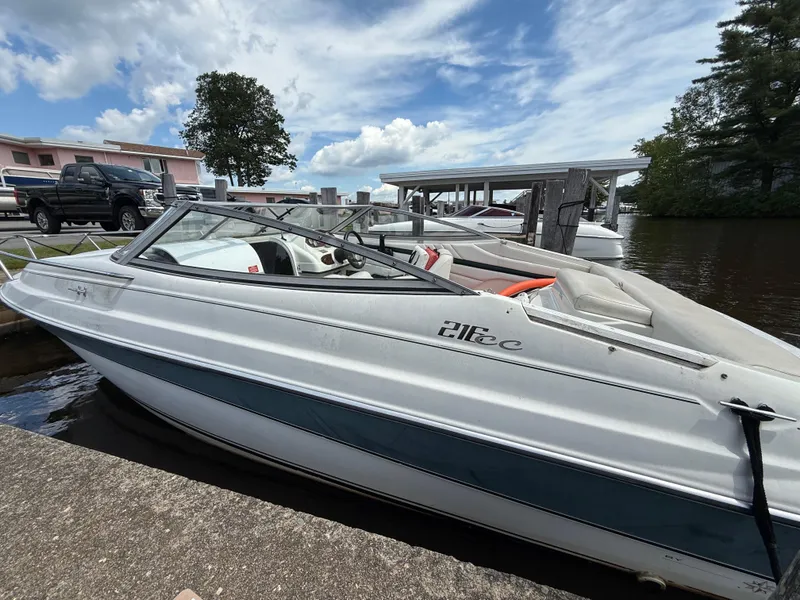 Slide: The Image of 1996 Doral 216 Cuddy boat docked by the water under a partly cloudy sky. - 12
