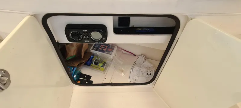 Slide: The Image of Open storage compartment on a 2012 Sea Ray 260 Sundeck with radio and miscellaneous items. - 18