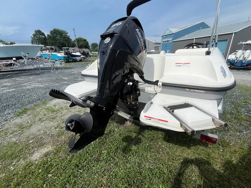 Slide: The Image of 2021 Bayliner Element E16 boat with Mercury outboard motor, parked on gravel. - 2