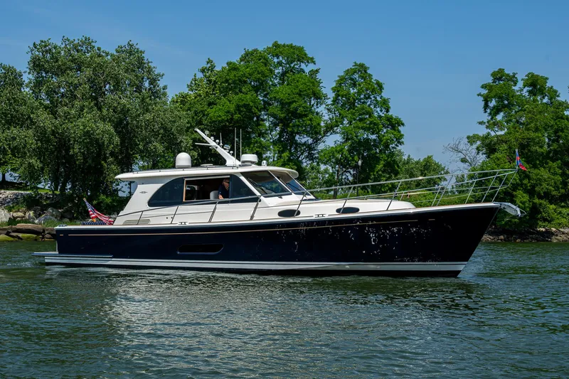 Slide: The Image of 2017 Grand Banks 44 Eastbay SX yacht with American flag, cruising near lush greenery. - 7