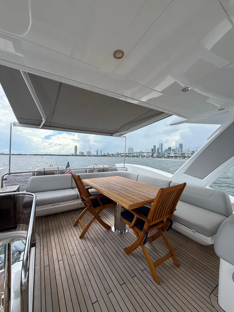 Slide: The Image of Luxurious Sunseeker Manhattan 68 yacht deck with wooden table, chairs, and city skyline view. - 18