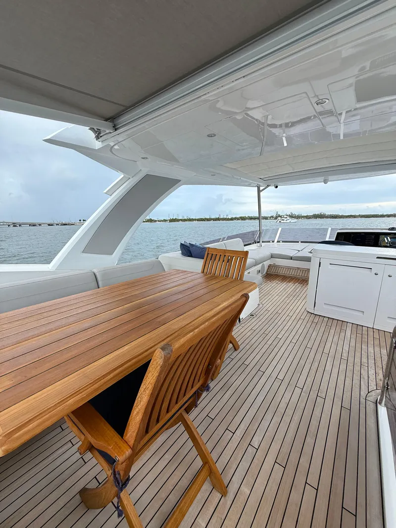 Slide: The Image of Luxurious Sunseeker Manhattan 68 yacht deck with wooden table, seating, and ocean view. - 20