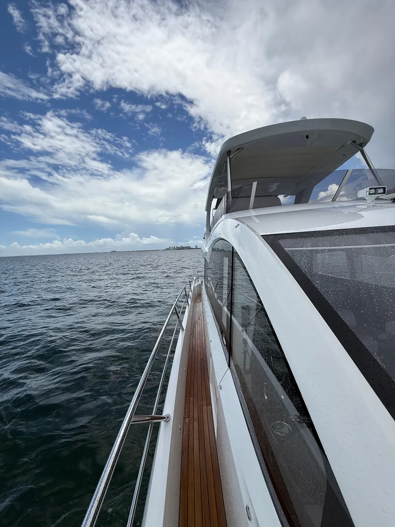 Slide: The Image of 2022 Sunseeker Manhattan 68 yacht cruising on open water under a partly cloudy sky. - 9